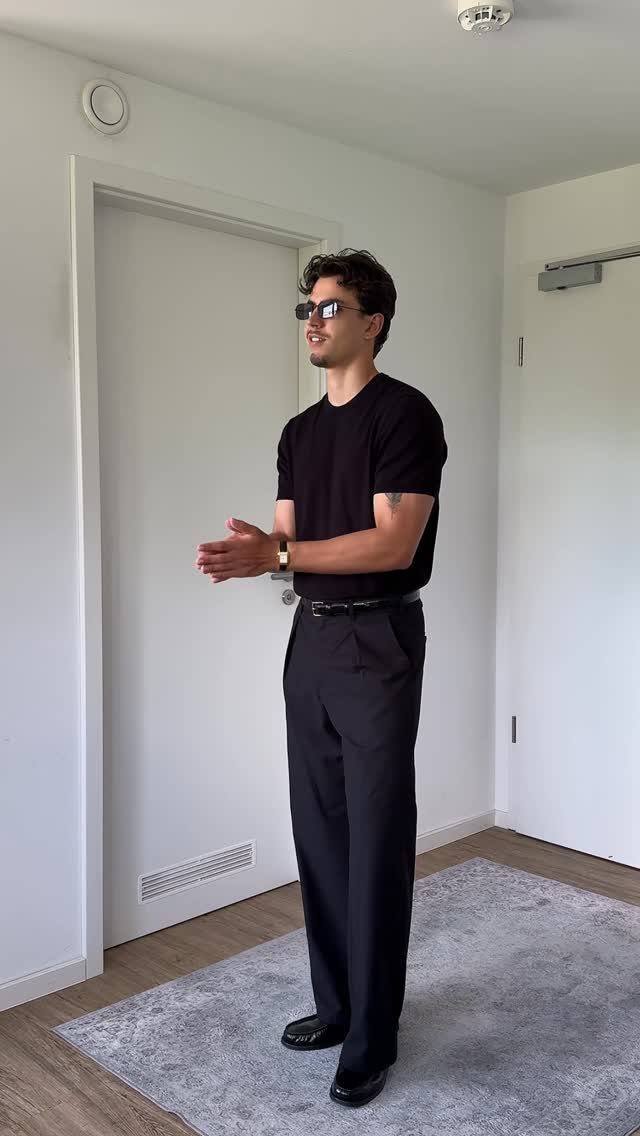 A man wearing an all black outfit with sunglasses and a black t-shirt.
