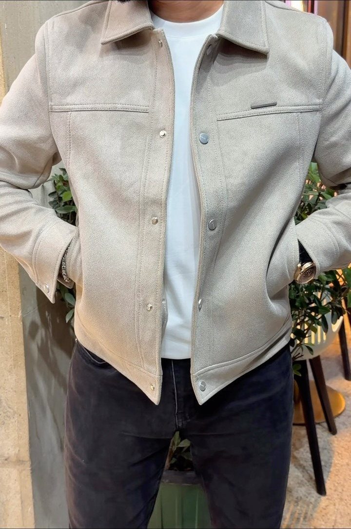 Man wearing a beige corduroy jacket, white t-shirt, and black jeans.