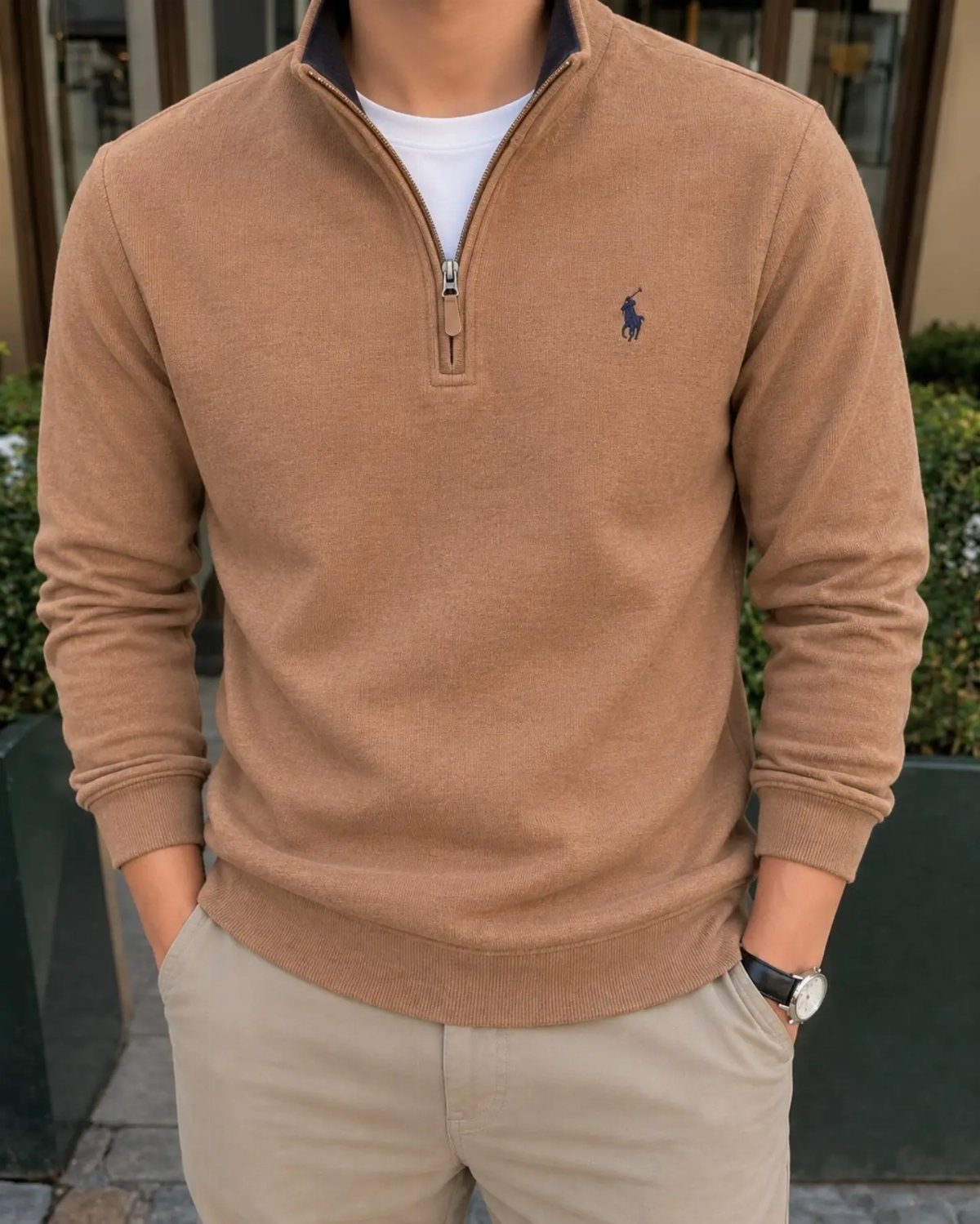 Man wearing a tan quarter-zip sweater with beige trousers and a white undershirt.