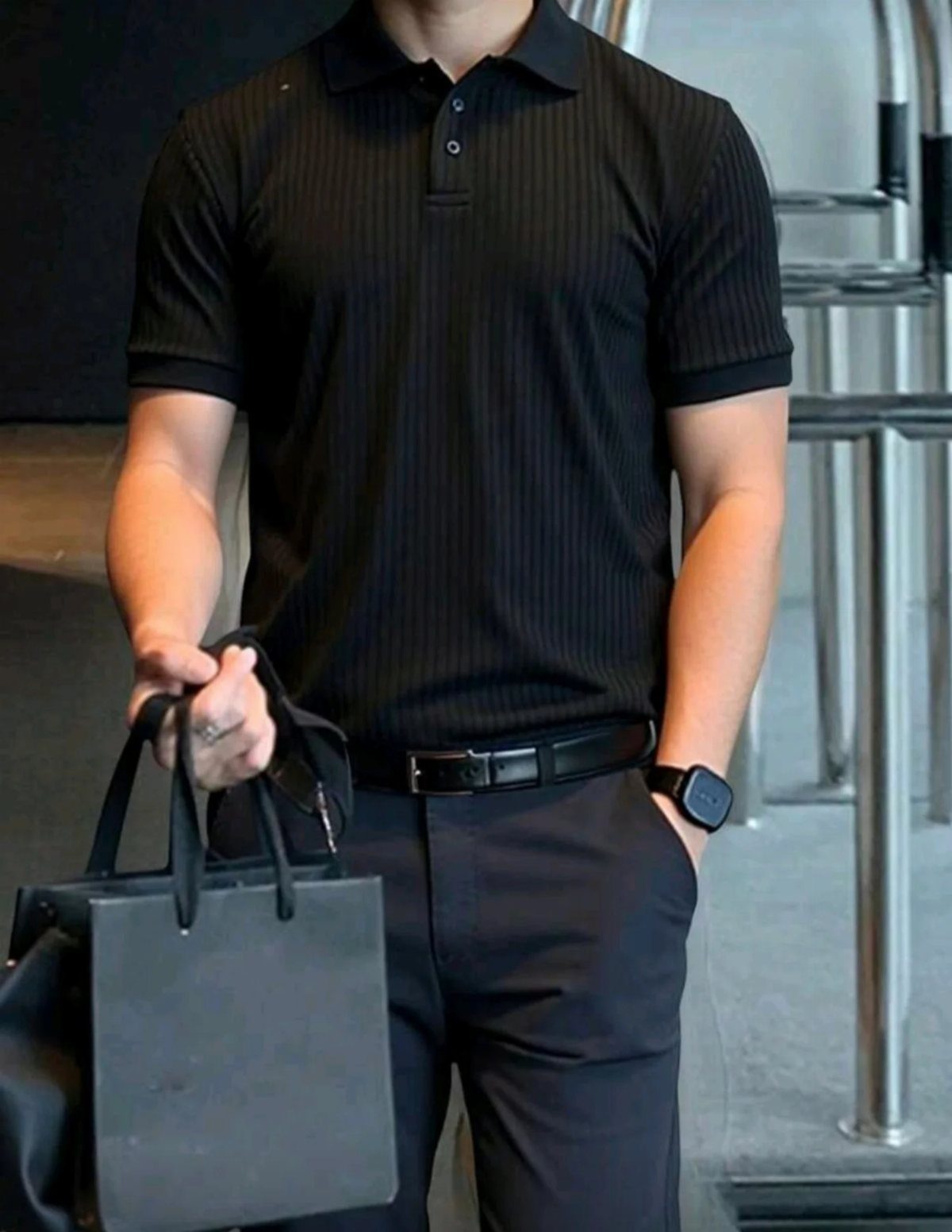 Man wearing a black striped polo shirt, black trousers, and a black leather belt.