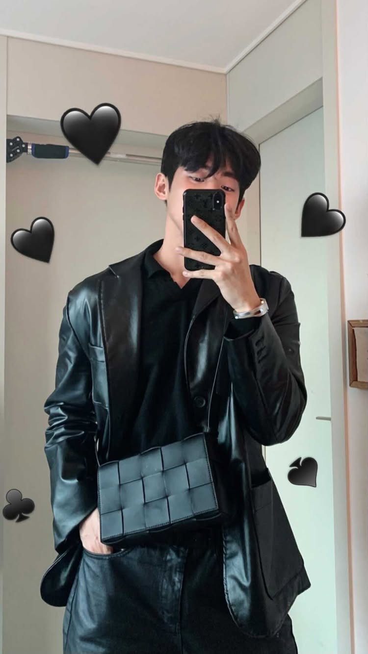 Man in an all-black leather blazer and shirt taking a mirror selfie.