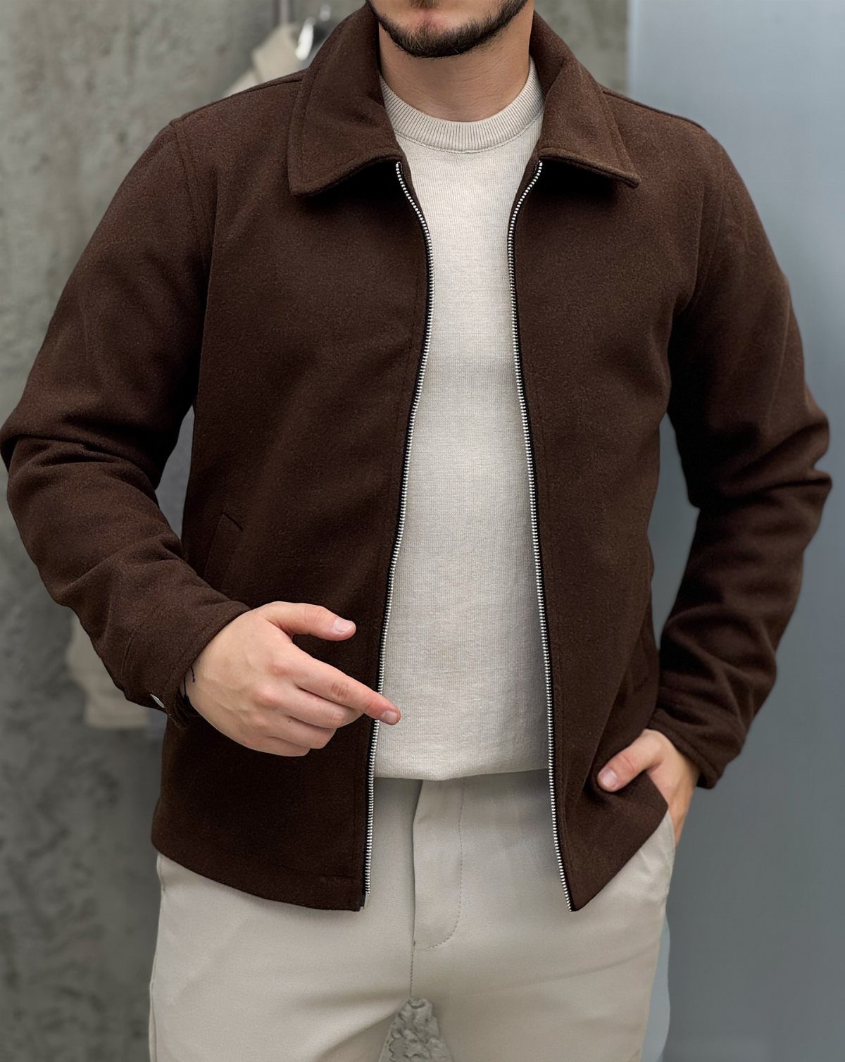Man wearing a brown textured jacket, cream sweater, and light beige trousers.