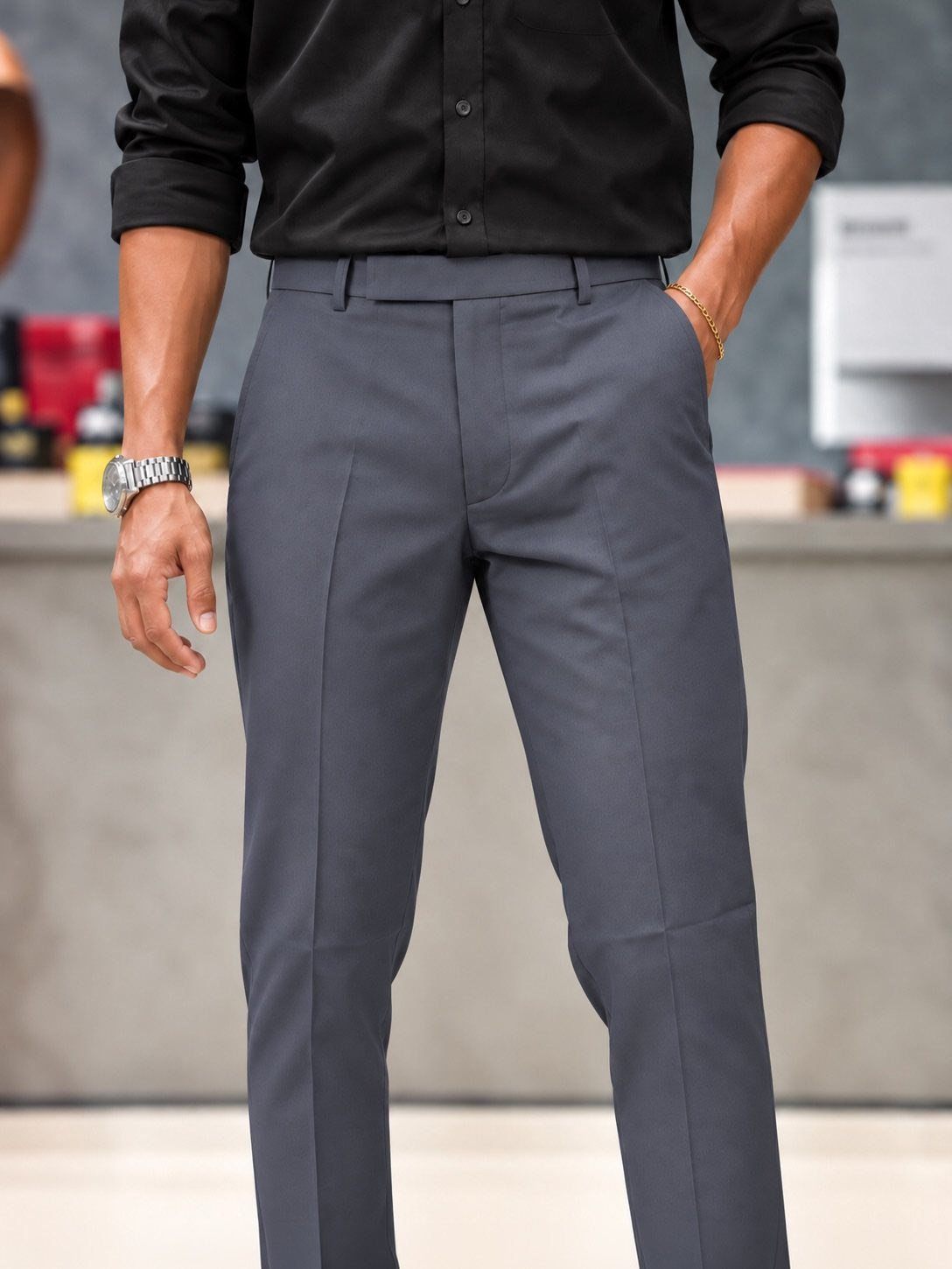 Man wearing a black button-down shirt and grey trousers with a silver watch.