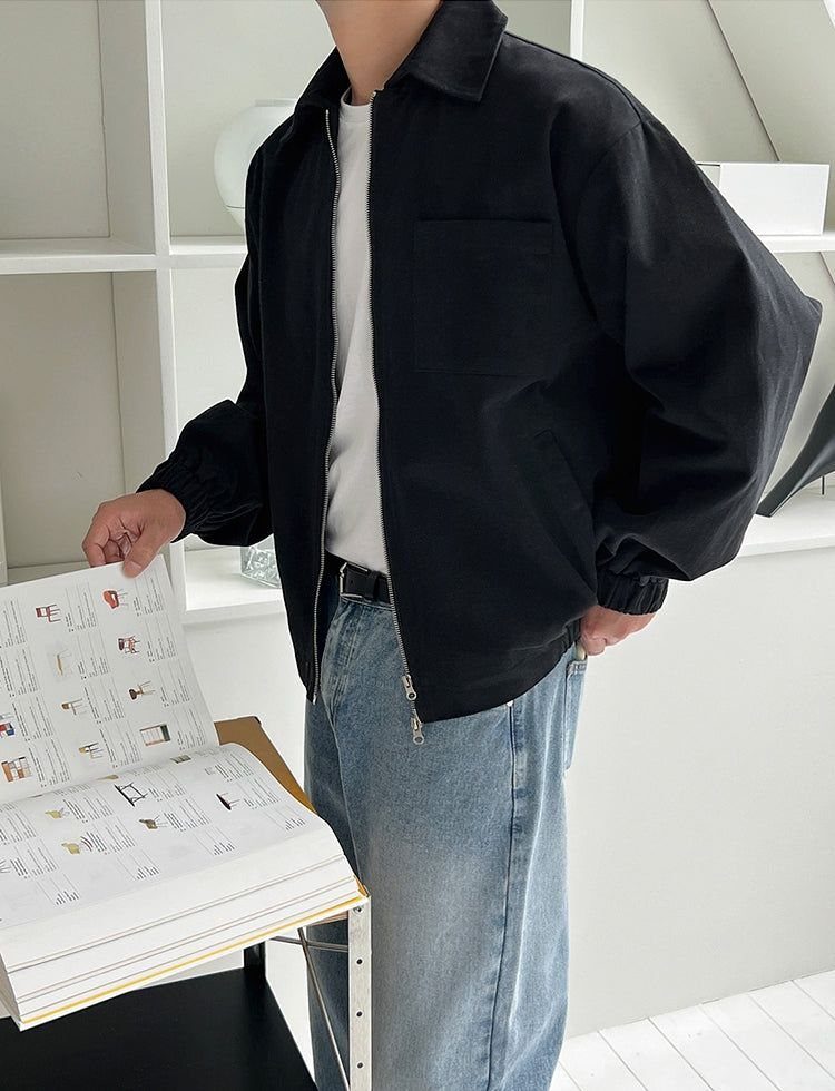 A person wearing a black lightweight jacket, a white t-shirt, and light blue denim jeans.