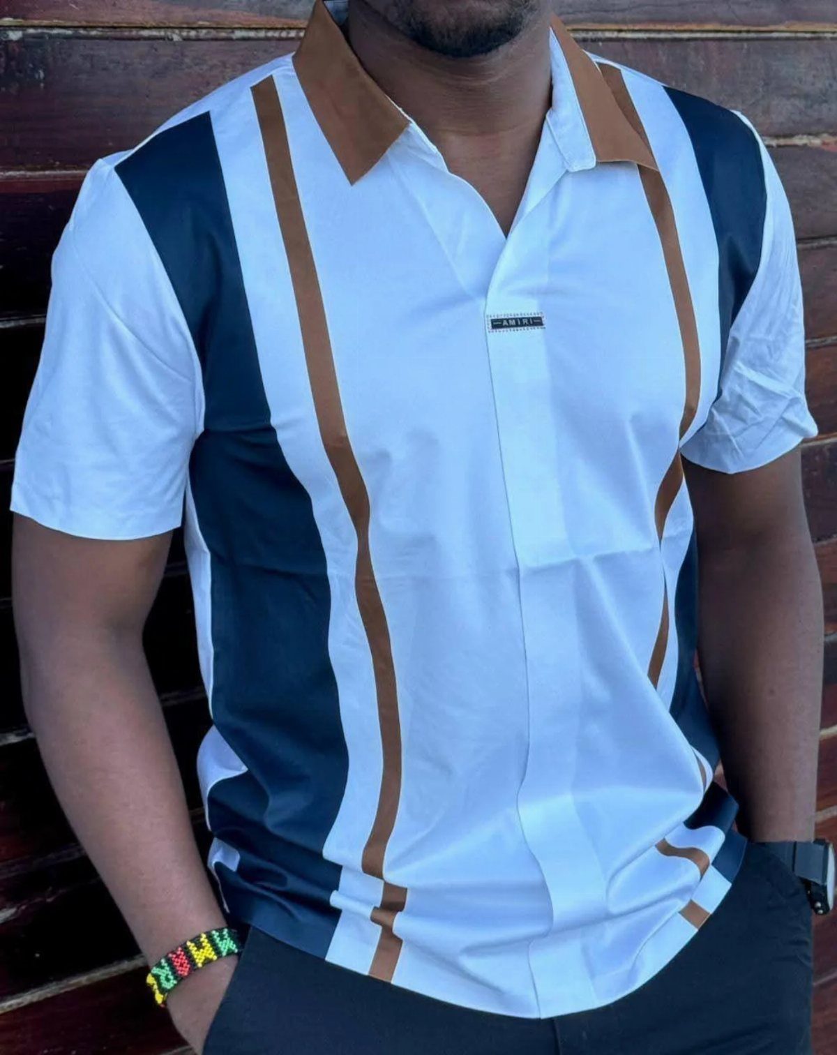 Man wearing a white short-sleeved shirt with vertical navy and tan stripes.