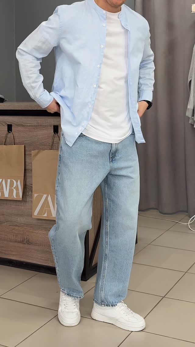 Man wearing a light blue shirt, white t-shirt, light blue jeans, and white sneakers.