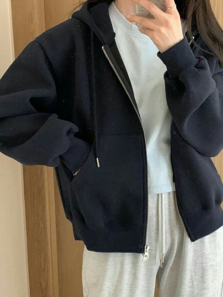 A person wearing a navy hoodie, light blue t-shirt, and grey sweatpants in a mirror selfie.