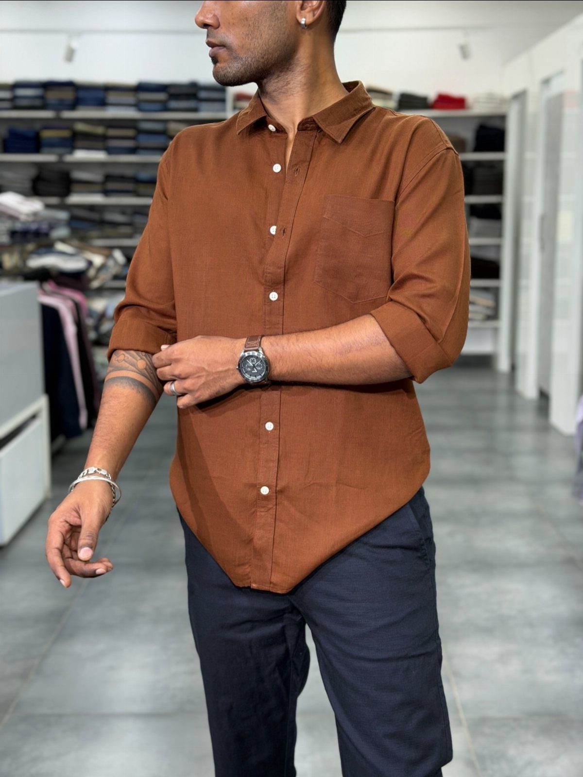 Man wearing a burnt orange button-down shirt paired with dark navy blue trousers.