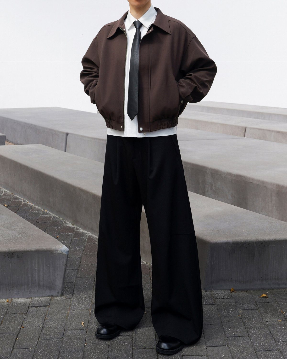 A person wearing a brown cropped jacket with black wide-leg pants and black shoes.