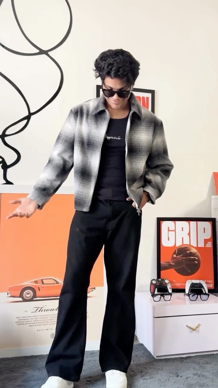 A person posing in a plaid cropped shacket and black wide-leg trousers.