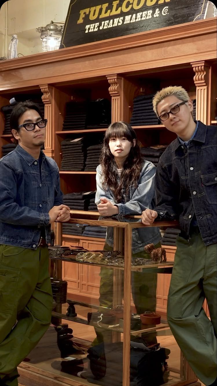 Three people posing in a denim shop wearing various denim jackets and olive green cargo pants.