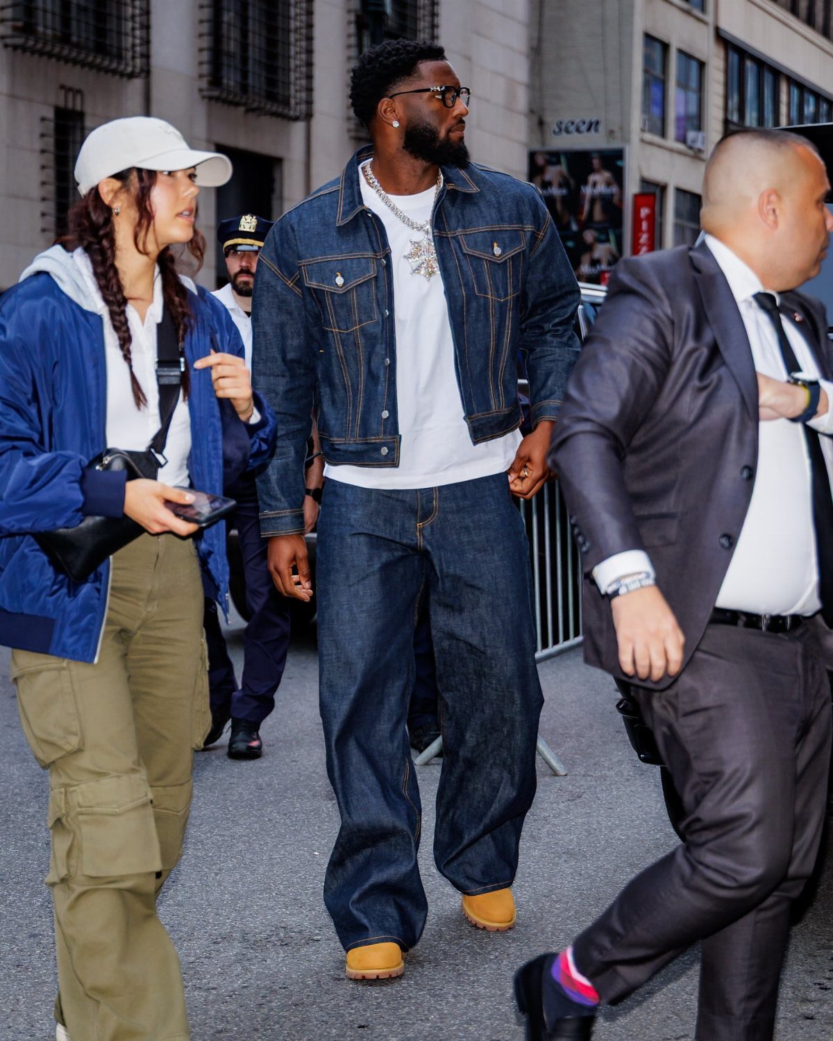Man walking in a city wearing a denim jacket, white t-shirt, and baggy denim jeans.