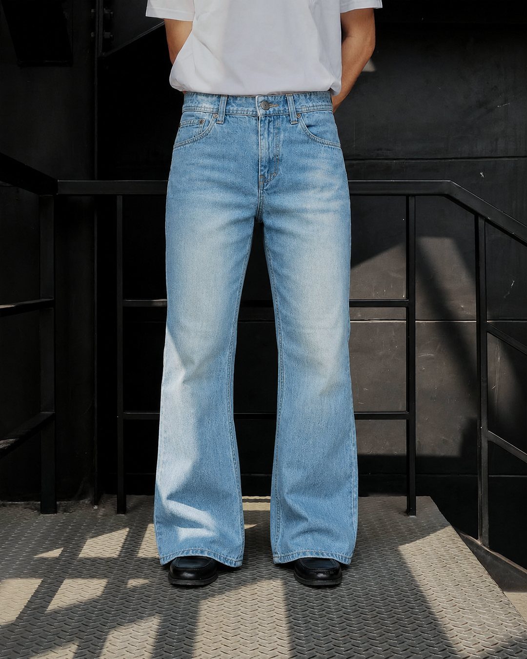A person wearing light blue boot cut denim jeans and a white t-shirt.