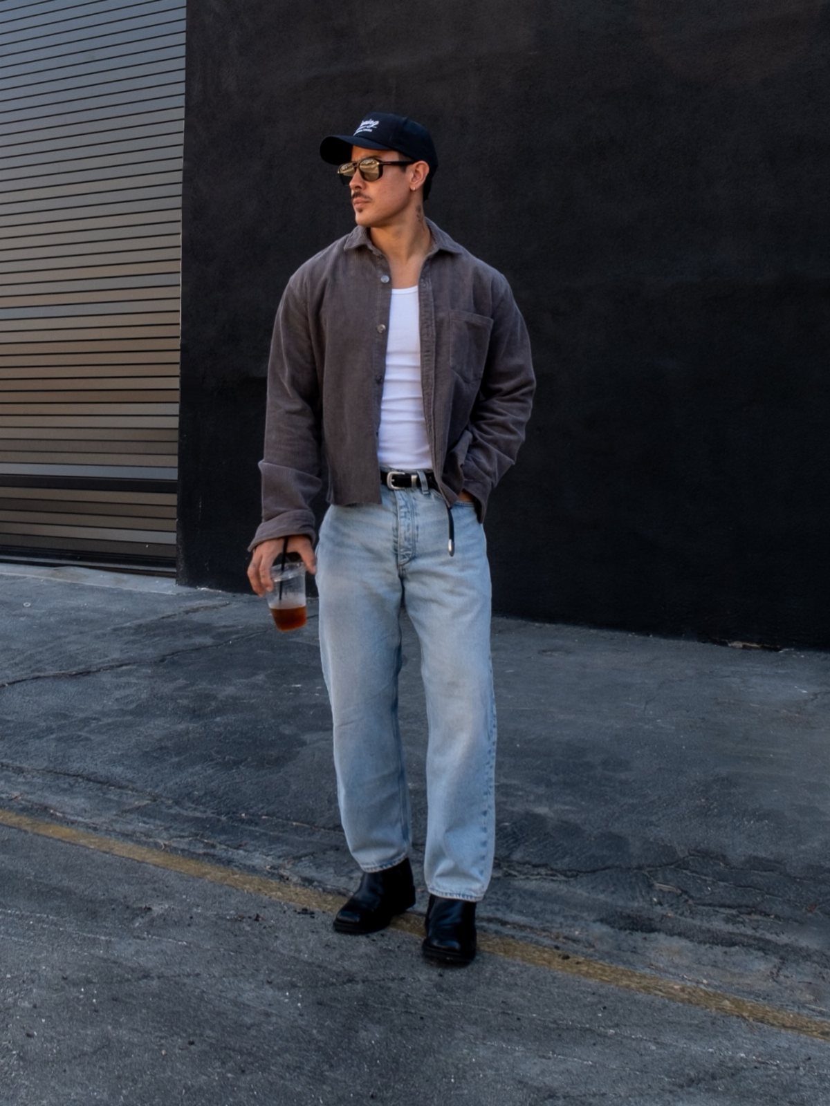 Man wearing a dark grey shirt, white t-shirt, and light blue denim jeans.