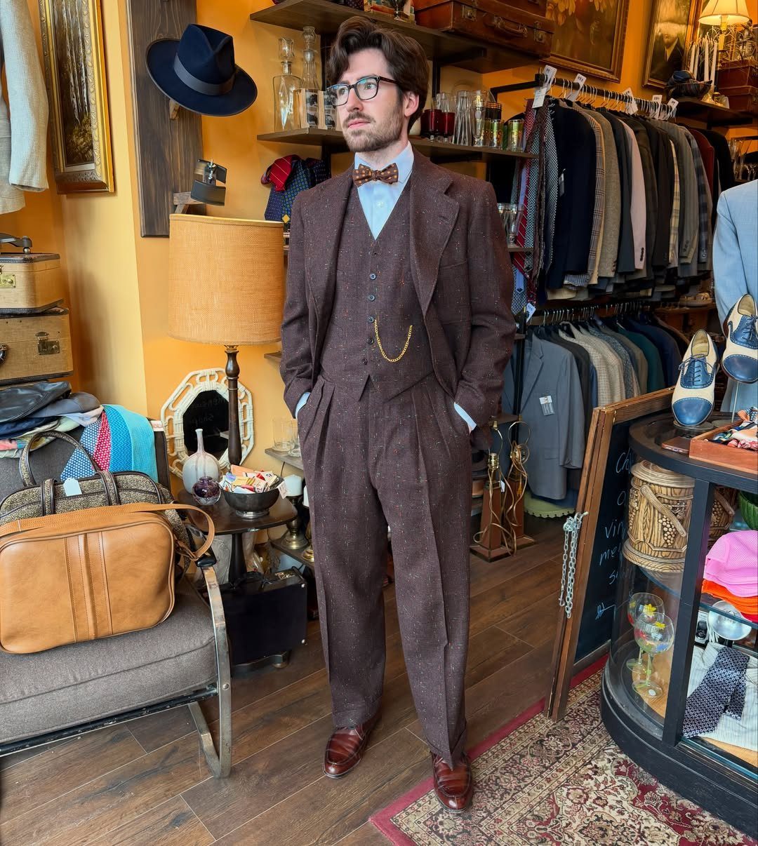 Man wearing a vintage brown three-piece wool suit with a gold pocket watch chain.