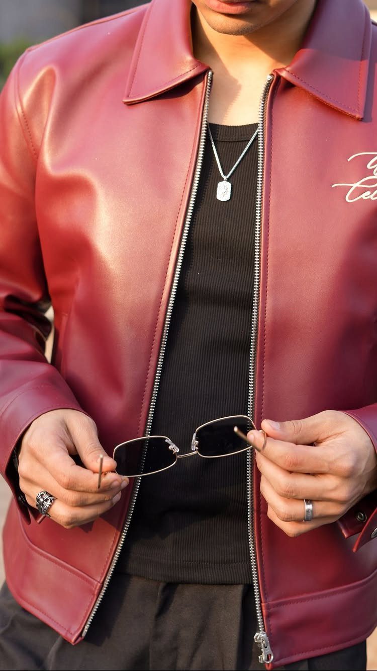 Man wearing a vibrant red leather jacket over a black ribbed shirt and silver necklace.