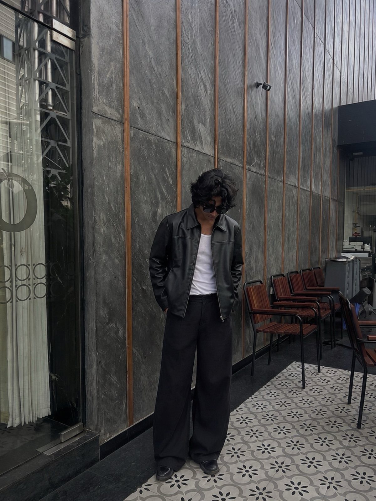 Person wearing a black leather jacket with wide-leg black tailored trousers and a white t-shirt.