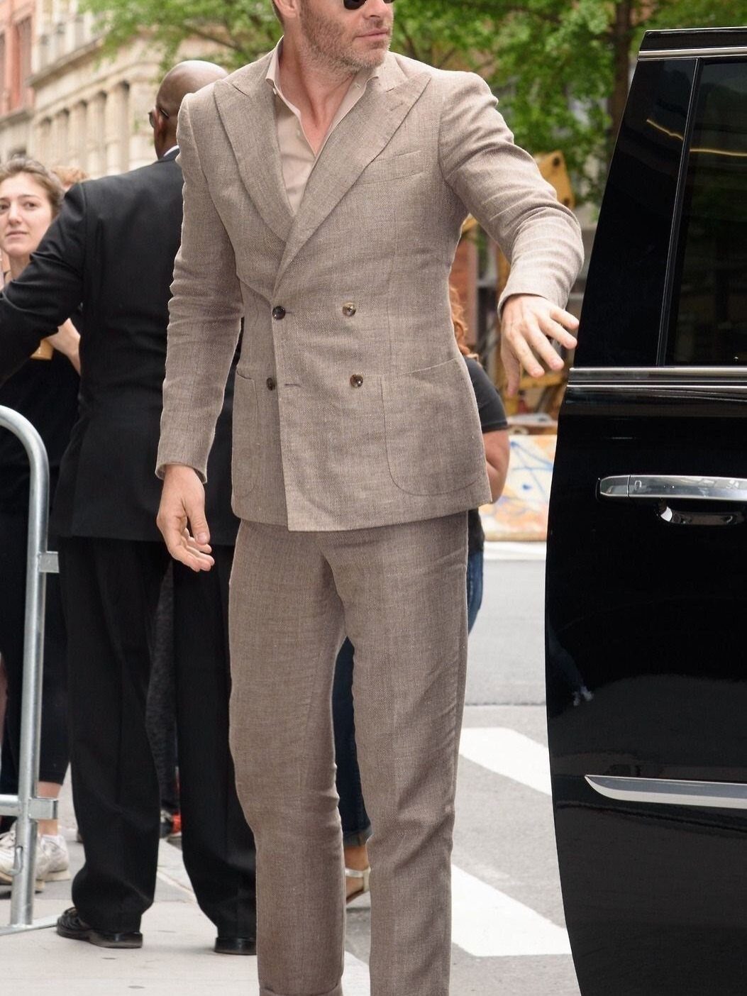 Man walking in a tan linen blazer and matching linen pants.