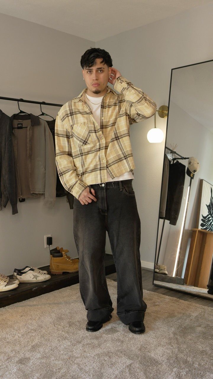 Man wearing a yellow plaid shirt, white t-shirt, and dark grey wide-leg jeans.