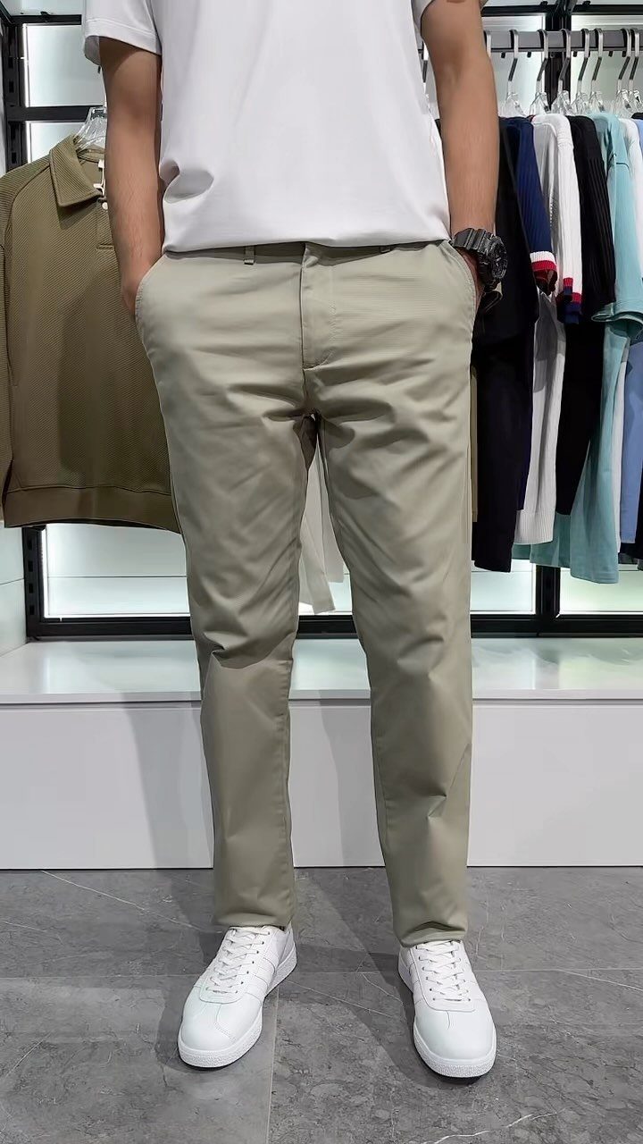 A man wearing a white t-shirt and khaki chinos with white sneakers.