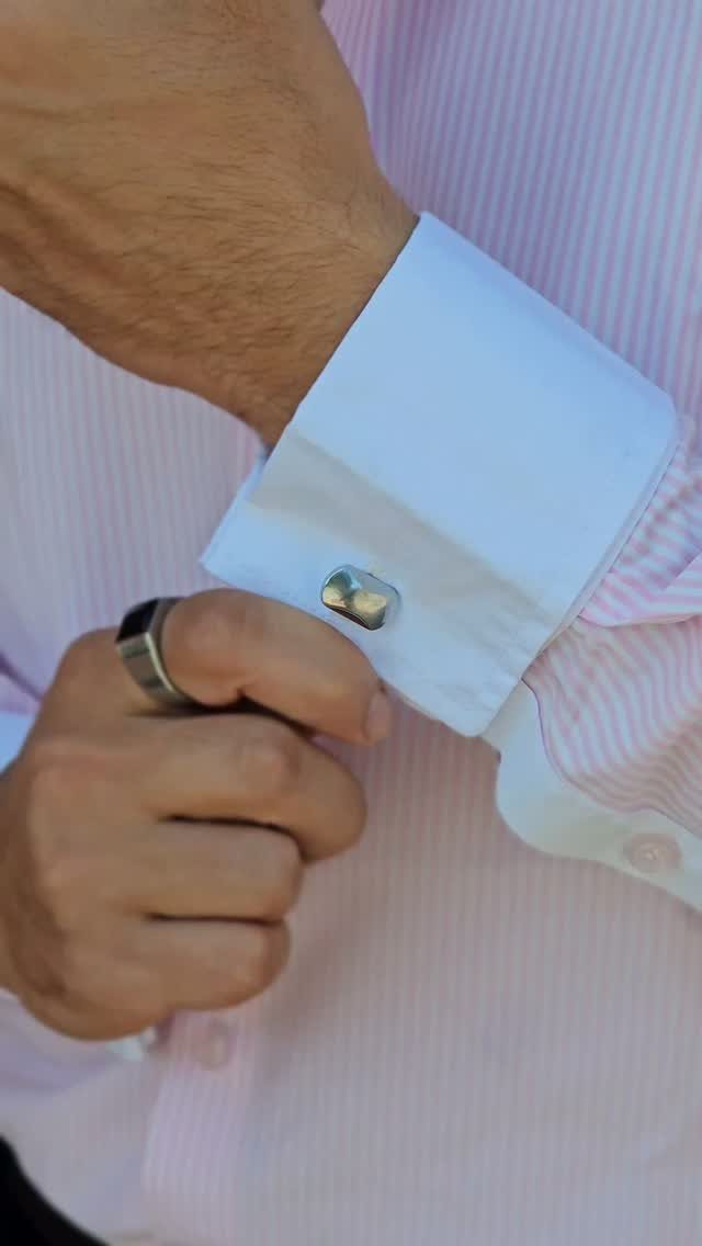 A close-up of a white French-cuff shirt sleeve with a silver cufflink.