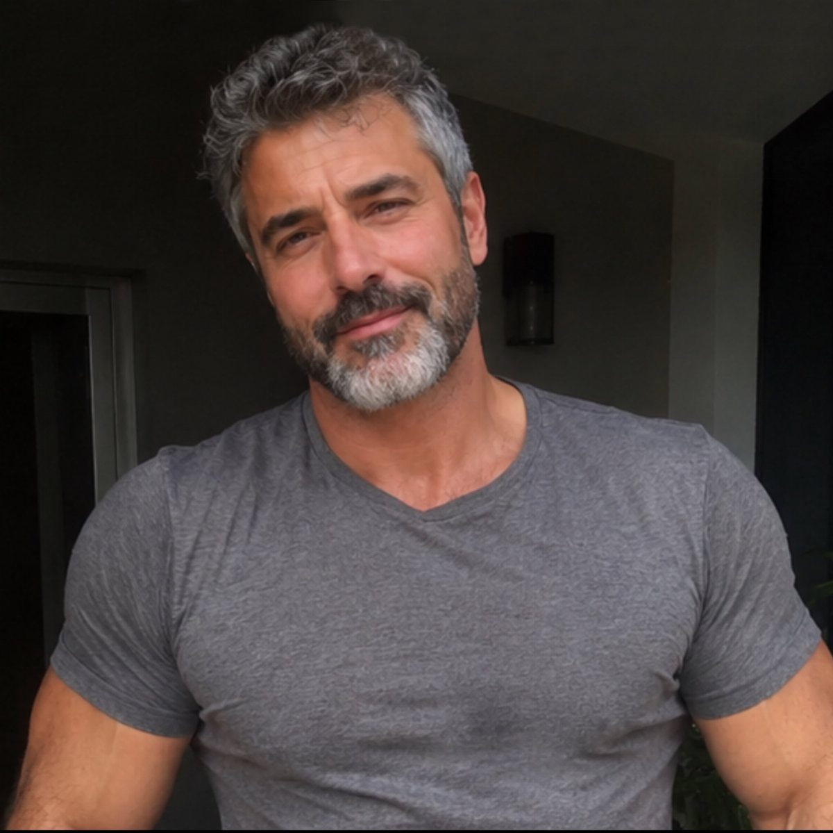 A middle-aged man with salt-and-pepper hair and a neat beard smiling.