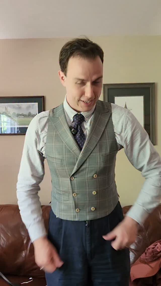 Man wearing a grey plaid double-breasted vest with a tie and light blue shirt.