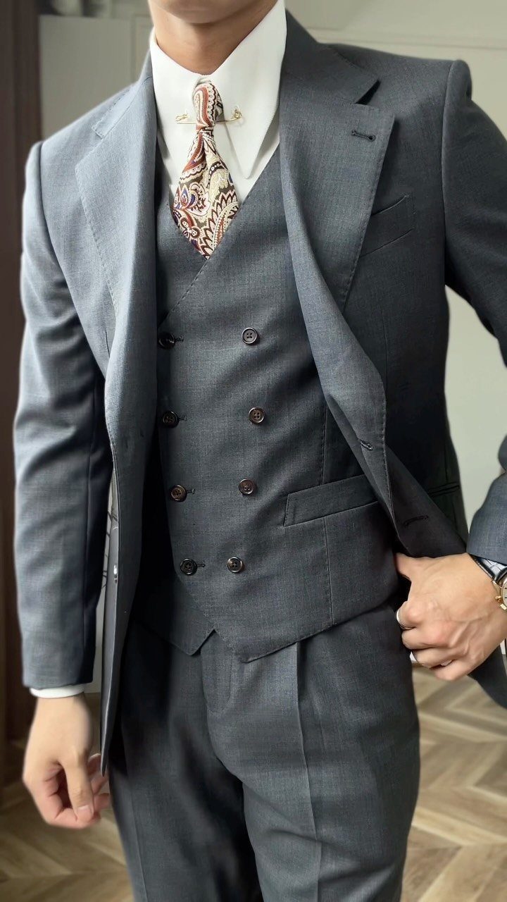 A man dressed in a grey double-breasted suit vest and matching jacket.