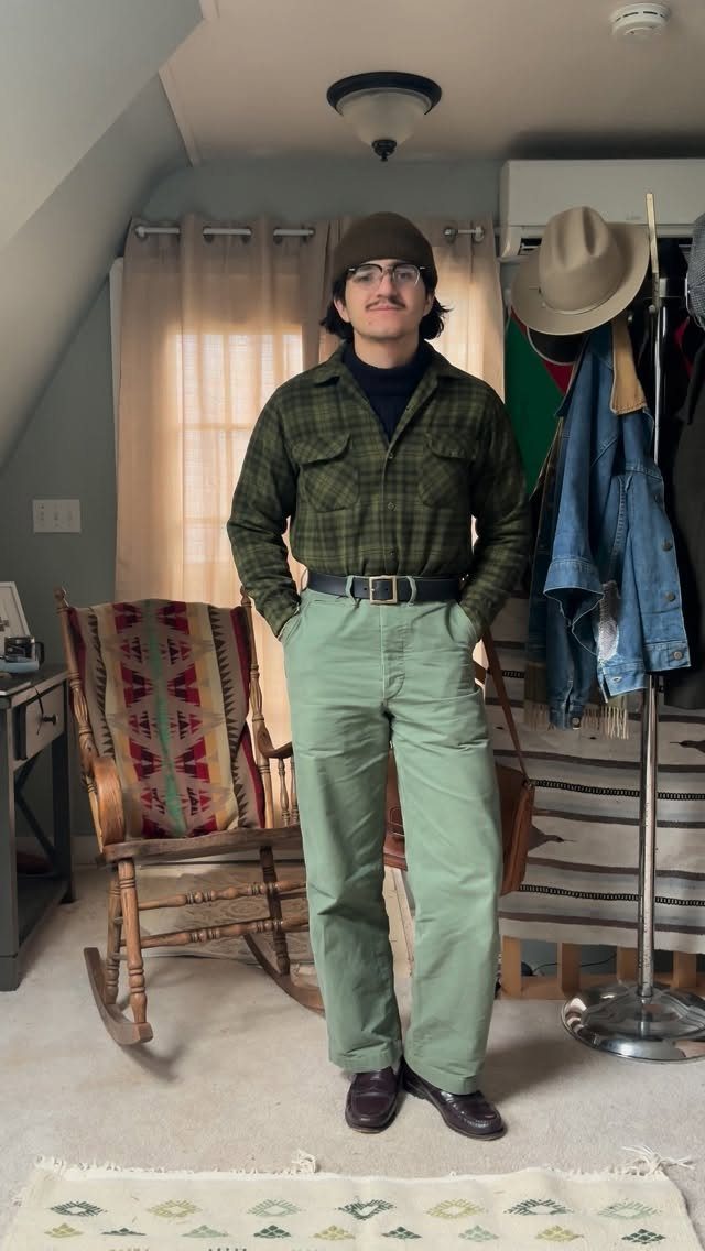 Man posing in a green plaid flannel shirt, light green chinos, and dark brown leather shoes.