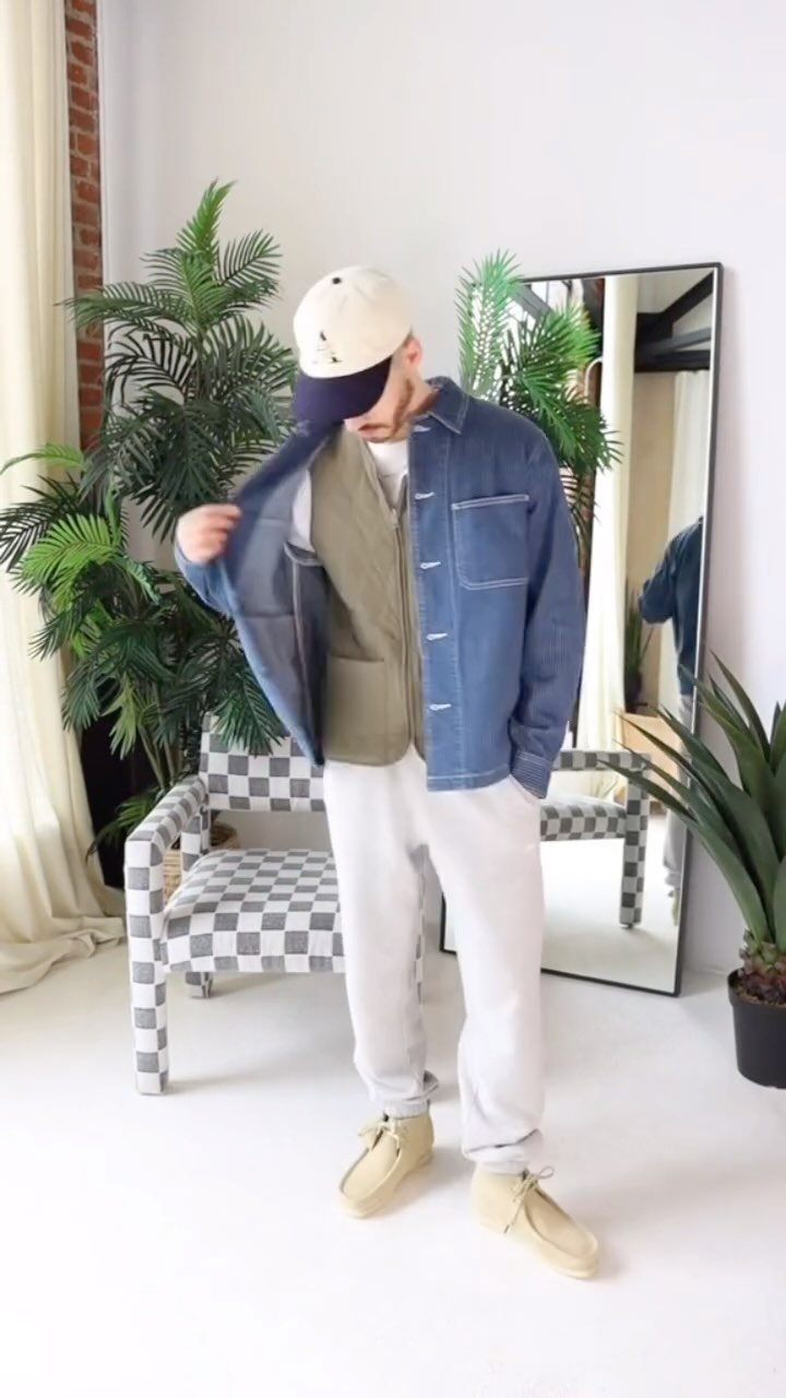Man wearing a denim jacket, olive vest, white trousers, and tan suede chukka boots.