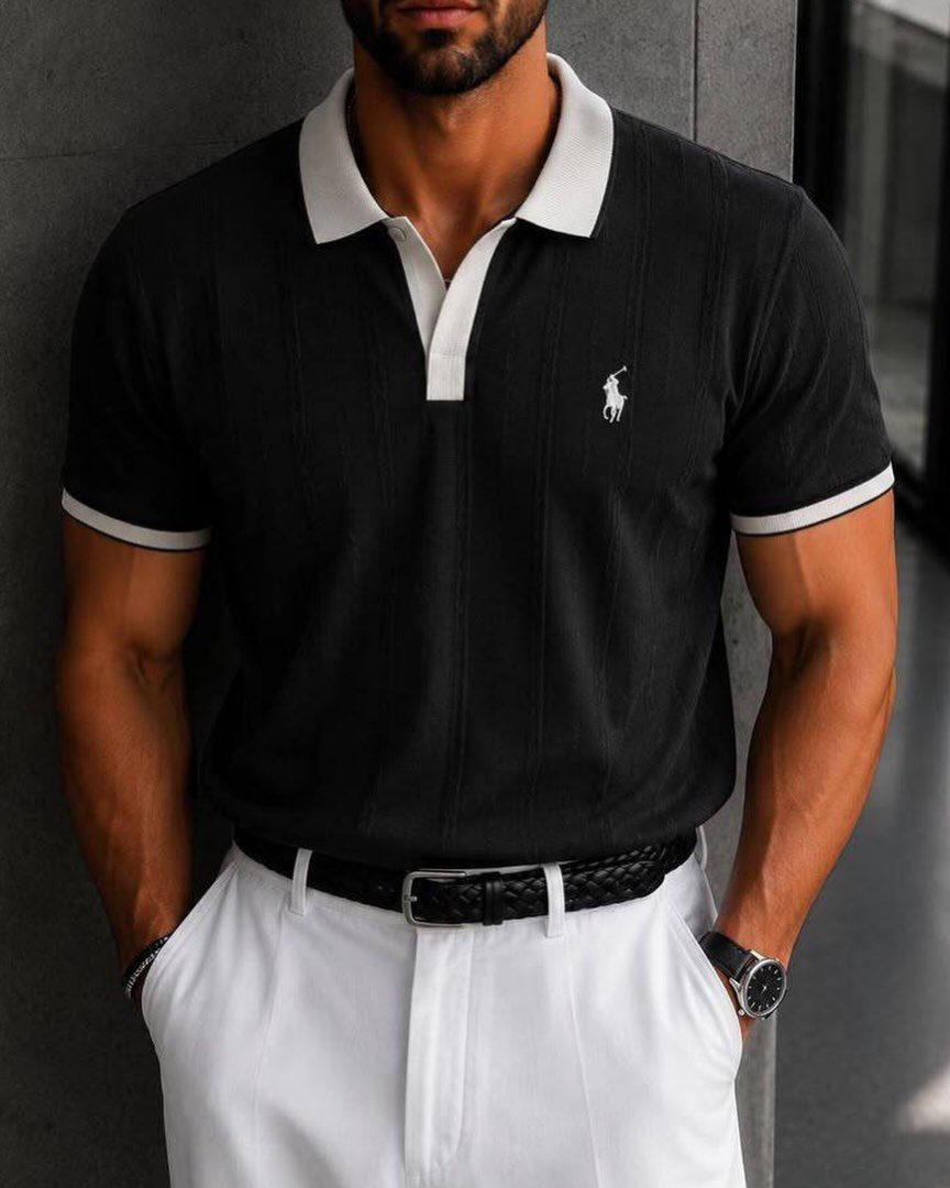 Man wearing a black polo shirt with white trim and white trousers.