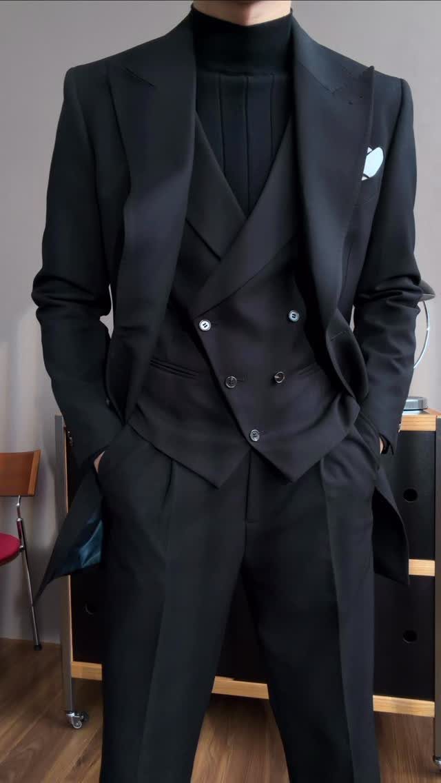Man wearing a black three-piece suit with a black turtleneck sweater.