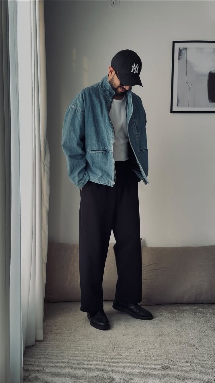 Man wearing an oversized denim jacket, white t-shirt, and black wide-leg trousers.