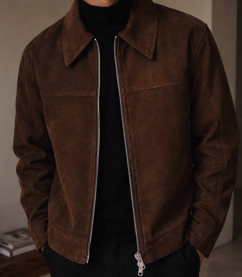 A person wearing a brown suede jacket over a black turtleneck sweater.