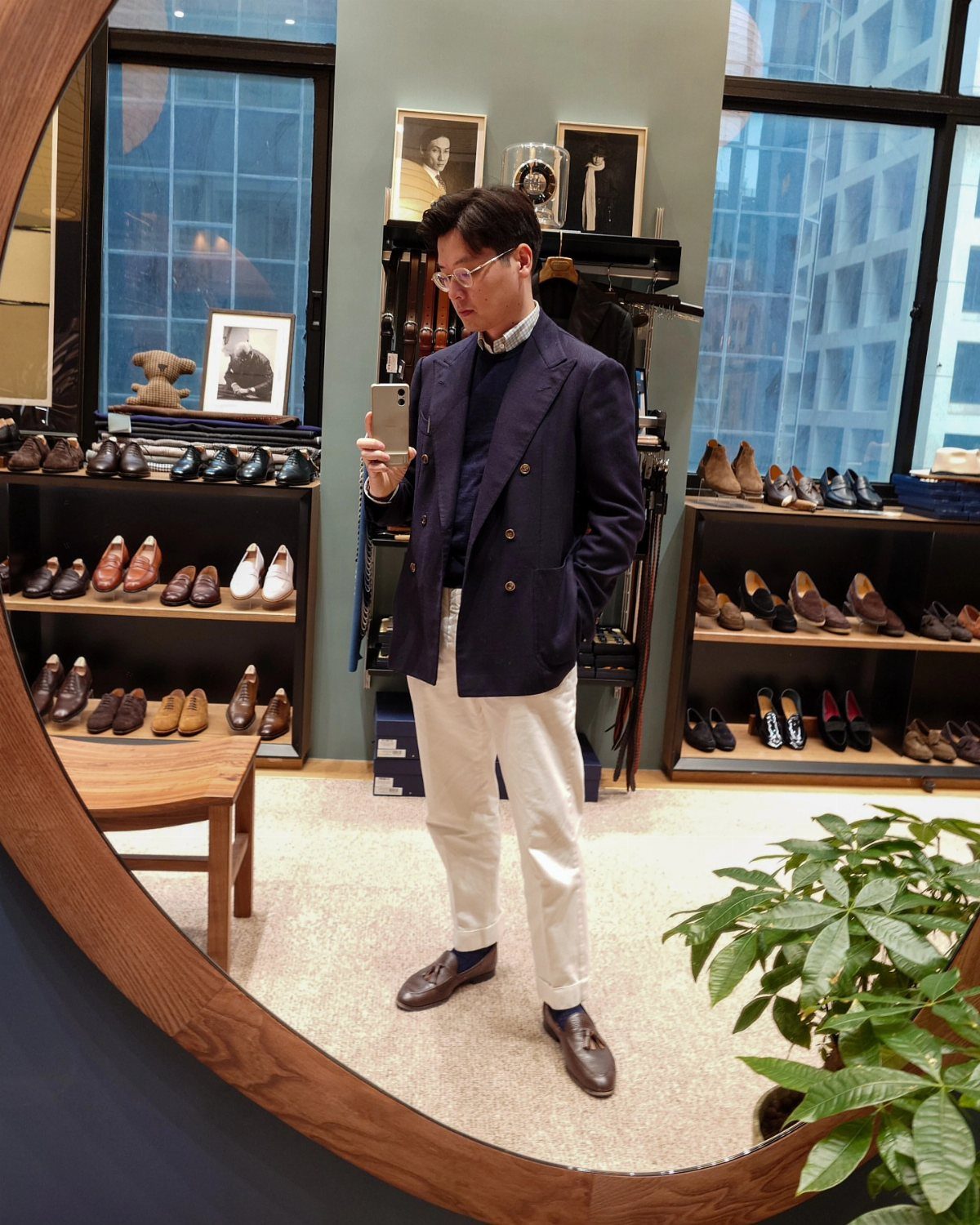Man in a navy sport coat and crew neck sweater posing in a mirror.