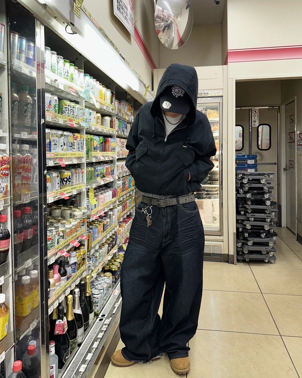A person wearing a dark hoodie, baggy dark jeans, and tan Timberland boots in a store.