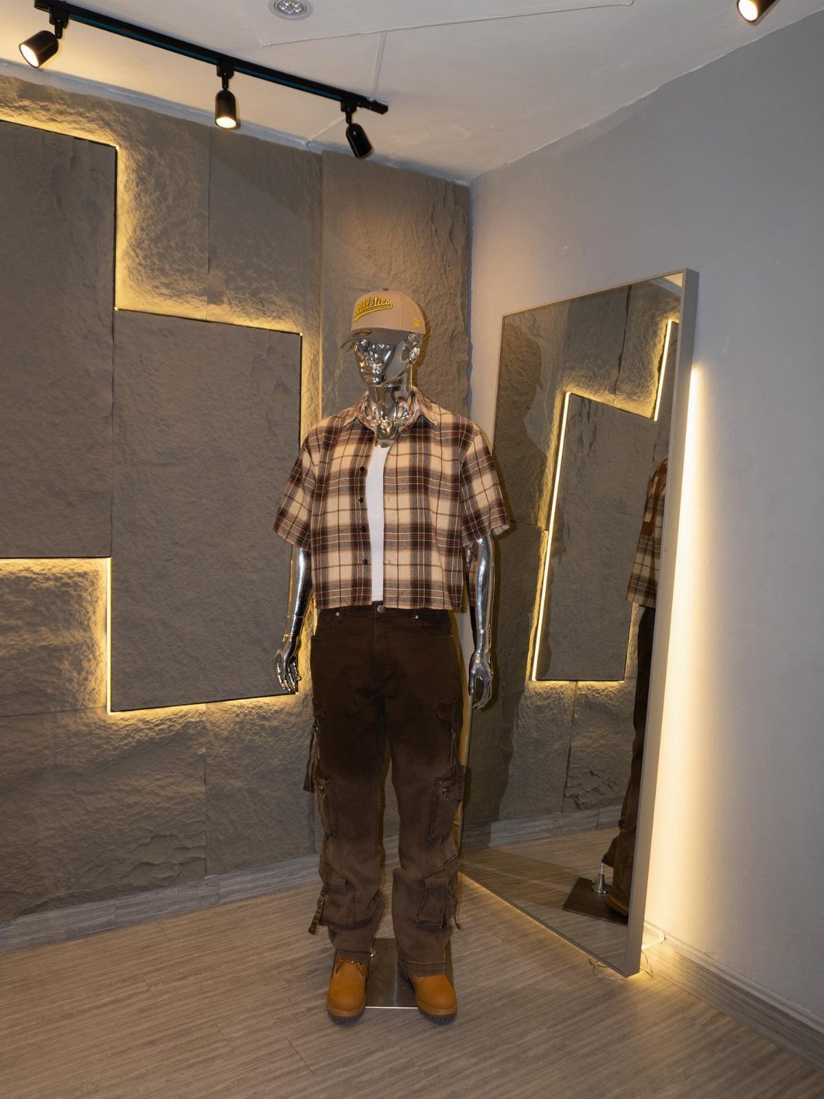 Mannequin wearing a plaid shirt, brown cargo pants, and yellow Timberland boots in a showroom.