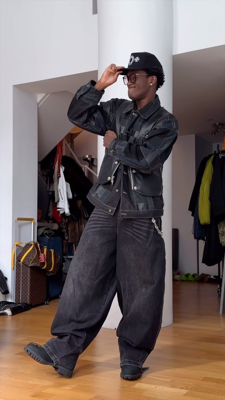 A person posing in a dark denim jacket, baggy jeans, and black Timberland boots.