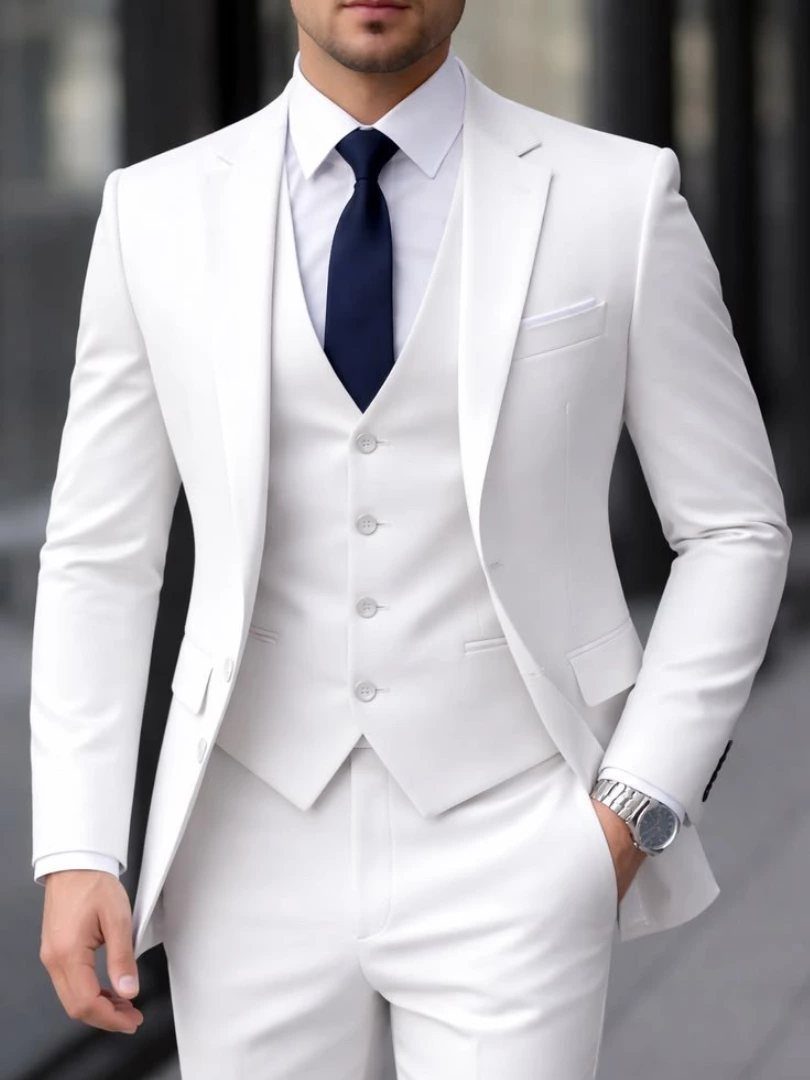 Man wearing a formal white three-piece suit with a navy blue tie.