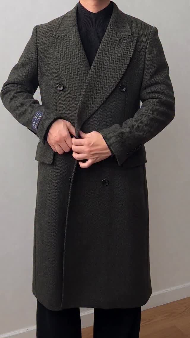 Man wearing a dark olive green double-breasted wool overcoat and a black turtleneck sweater.